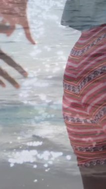 Sahilde yürüyen Afrikalı Amerikalı bir çiftin elleri üzerinde ışıkların animasyonu. Tatiller, tatiller ve rahatlama konsepti dijital olarak oluşturulmuş video.