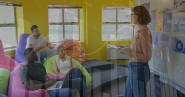 Ofiste oturan bir kadın, mali tablolar azalırken beyaz tahtada el kol hareketi yaparak iş arkadaşlarıyla konuşuyor. İşbirliği, takım çalışması, beyin fırtınası, yaratıcı, gayri resmi, dijital, analitik