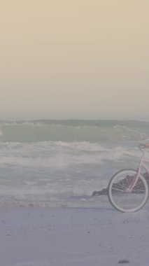 Spots of light against african american woman riding a bicycle at the beach. pedal day awareness concept