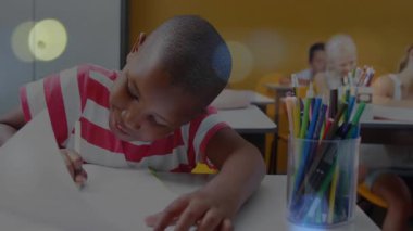 Kamera, oğlanın okuldaki masasına notlar yazdığını gösteriyor. Kalem inceleyen kıza odaklanıyor. Öğrenciler, eğitim, öğrenim, sınıf, takım çalışması, konsantrasyon, çeşitlilik