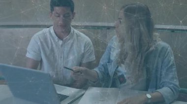 Adam, eğitim sırasında dizüstü bilgisayar kullanırken not tutan bir kadını işaret ediyor. İşbirliği, takım çalışması, öğrenme, eğitim, çalışma alanı, iletişim, danışmanlık