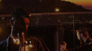 Çatıda çalan müzik grubunun vokalistleri davul çalarken ve ritim tutarken ortaya çıkıyor. Konser, şehir, gece hayatı, performans, melodi, ritim, uyum