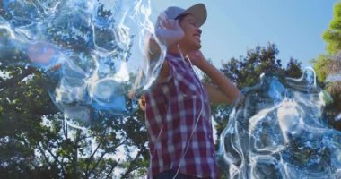 Güneş ışığı parkında müzik eşliğinde şarkı söyleyen bir kadın gövdenin etrafında mavi girdaplar yaratıyor. Müzik, ritim, canlılık, ifade, açık hava, dinginlik, hareket