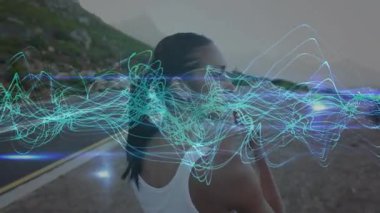 Sahil yolunda koşucu, sağIık teknolojisiyle omuz germeye başlayan dalgalanan dalgaları izliyor. Spor, sağlık, esneklik, doğa, teknoloji, canlılık, açık hava