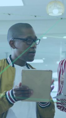 Erkek ve bayan meslektaşlar dizüstü bilgisayar ve tablet kullanıyorlar, ofiste iş konuşuyorlar..