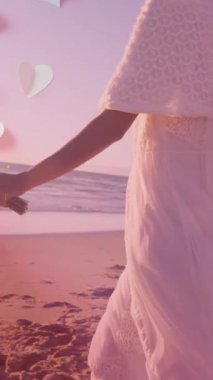 Mutlu çeşitliliğin üzerinde kalp animasyonu deniz kenarında koşan evli bir çift. Evlilik, aşk, ilişki, ev ve yaşam tarzı konsepti dijital olarak oluşturulmuş video.