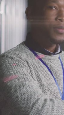 Sunucu odasında poz veren Afro-Amerikan bir adamın üzerindeki dünya ve ışıkların animasyonu. ağ, programlama, bilgisayarlar ve teknoloji konsepti dijital olarak oluşturulmuş video.