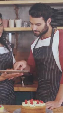 Kafedeki dijital tablet üzerinde tartışan çok ırklı iş arkadaşlarının üzerinde hareket eden grafiklerin animasyonu. Dijital bileşik, rapor, veri, iş, teknoloji, takım çalışması, yiyecek ve içecek işi.