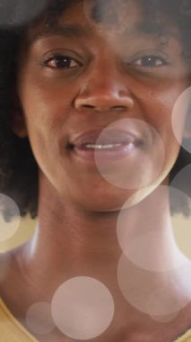 Animation of portrait of happy african american businesswoman over light spots. Global business and digital interface concept digitally generated video.