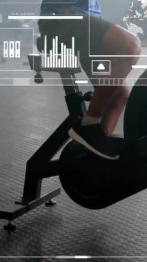 Spor salonunda eliptik bisikletlerle egzersiz yapan bir adamın veri işleme ve diyagramlarının animasyonu. Spor ve dijital arayüz konsepti dijital olarak oluşturulmuş video.