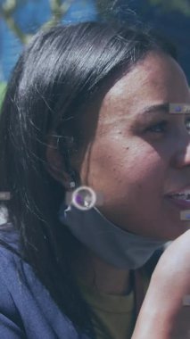 Sosyal medya simgeleri ve numaralarının akıllı telefonlu yüz maskeli kadın üzerinde canlandırılması. Küresel sosyal medya, iş dünyası, bulut hesaplama ve veri işleme kavramı dijital olarak oluşturulmuş video.