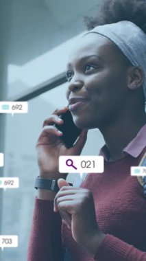 Animation of social media icons with growing numbers over african american woman using smartphone. Global social media, technology and digital interface concept digitally generated video.