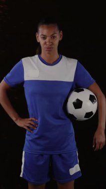 Arka planda duman patlamasına karşı elinde top tutan kadın futbolcunun dijital kompozit videosu. Spor fitness konsepti dijital kompozit