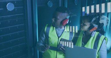 Teknik mühendisler sunucuları işaret edip dizüstü bilgisayarları kontrol ederken çizelgeler ve kodlar da izlemeyi etkinleştiriyor. Teknoloji, veri, analitik, yenilik, siber güvenlik, dijital, kuruluş