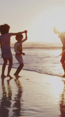 Noel 'in animasyonu, gün batımında kumsalda yürüyen mutlu Afrikalı Amerikan ailesinin üzerinde. Noel, gelenek, kutlama ve aile zamanı konsepti dijital olarak oluşturulmuş video.