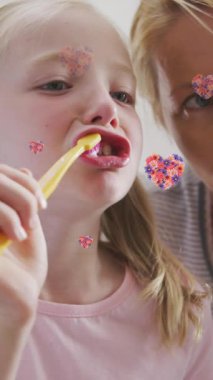 Beyaz tenli anne ve kızının dişlerini fırçaladığı çiçek kalplerinin animasyonu. Aile hayatı, çocukluk, aşk ve bakım konsepti dijital olarak oluşturulmuş video.