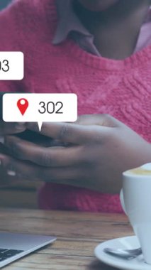 Animation of social media icons over african american woman with face mask using smartphone. Global covid 19 pandemic, social media, and digital interface concept digitally generated video.