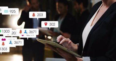 Yetişkin bir kadın tableti tıklayarak sosyal medya tebligatları yaratıyor iş dünyasının toplantı ekibini sel baskınına uğratıyor. Teknoloji, işbirliği, dijital, iletişim, ağ oluşturma, yenilik, profesyonel