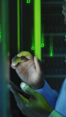 Animation of binary coding over african american male it engineer and computer servers. Global computing and data processing concept digitally generated video.