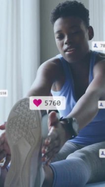 Sosyal medya simgelerinin ve numaraların evde egzersiz yapan Afrikalı Amerikalı kadın üzerinde canlandırılması. Dijital olarak oluşturulmuş küresel sosyal medya, hesaplama ve veri işleme kavramı.