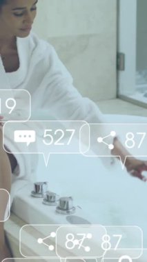 Bornozlu bir kadının banyo yapması ile ilgili sosyal medya tebligatları. Yaşam tarzı, kişisel bakım, rahatlama, dijital arayüz, sosyal ağ ve iletişim, dijital olarak oluşturulmuş video.