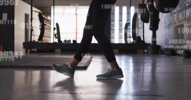 Kadın spor salonunda zıplıyor. Sayısal üstüste bindiğini gösteriyor. Sonra da ip atlayıp dayanıklılığını gösteriyor. Fitness, çeviklik, kardiyo, egzersiz, motivasyon, spor, aktif