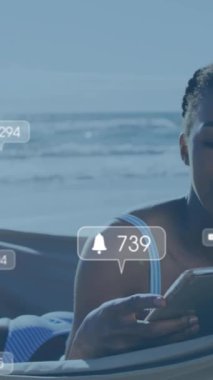 Animation of social media reactions over happy african american woman in hammock on beach. Holidays, vacations and relax concept digitally generated video.