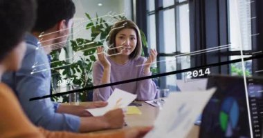 Konferans masasında sunum yapan bir kadın iş verilerini iş arkadaşı olarak inceliyor. Profesyonel, işbirliği, analitik, büyüme, yenilik, modern, stratejik