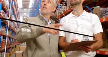 Kıdemli yönetici, yeni trendlere dikkat çekerken hologram zaman çizelgesini etkinleştiren depo raflarını işaret ediyor. Teknoloji, lojistik, yenilik, veri görselleştirme, üretkenlik, sanayi, şirket