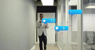 Akıllı telefonlara konuşan bir adam, iş arkadaşının nişan takibi etrafında sosyal medya simgeleri oluşturuyor. İşbirliği, dijital iletişim, modern çalışma alanı, profesyonel ağ, teknoloji, takım çalışması, yenilik