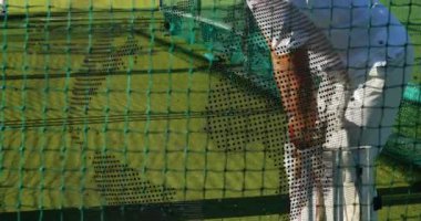 Kriket vurucusu bovling topunu antreman ağlarına fırlatıyor. Atletik, spor, eğitim, açık hava, rekabetçi, enerjik, hareketli