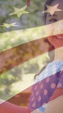 Amerika bayrağının parktaki gülümseyen kızın bayrağını dalgalandırması. Vatanseverlik, bağımsızlık ve kutlama konsepti dijital olarak oluşturulmuş video.