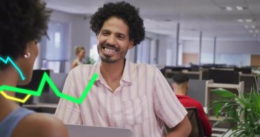 Adam iş arkadaşını selamlıyor ve iş toplantısına başlıyor. Dizüstü bilgisayarında yeşil mavi grafikleri canlandırıyor. İşbirliği, veri görselleştirme, takım çalışması, modern, profesyonel, finansal, analitik