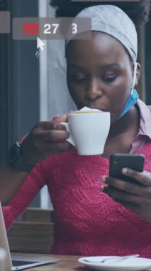 Kafe 'de akıllı telefon kullanan Afrikalı Amerikalı bir kadın hakkında sosyal medya bildirimleri. küresel iletişim teknolojisi ve sosyal ağ konsepti dijital olarak oluşturulmuş video.