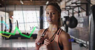 Spor salonunda atlama halatı tutan kadın antrenör yeşil-sarı fitness çizelgelerini fırlatıyor. Fitness, egzersiz, analitik, sağlık, güç, canlılık