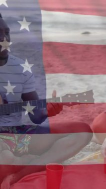 Amerika bayrağının animasyonu, yazın kumsalda gitar çalan mutlu arkadaşlara göre. Amerikan vatanseverliği, çeşitlilik ve tatil konsepti dijital olarak oluşturulmuş video.