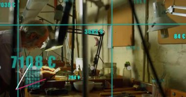 Kıdemli esnaf lambanın altındaki bileşeni ayarlar, teknolojik verileri yükselen kılavuz montajı destekler. Zanaatkar, atölye, teknik, hassasiyet, zanaat, yenilik, manuel