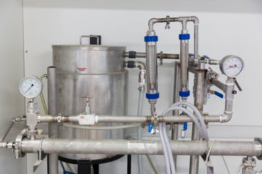 Paslanmaz çelik ünite düz dizayn gösteriyor. Tank, boru, vana ve göstergeler düz duvara dayanıyor. Endüstriyel, makine, ekipman, mühendislik, otomasyon, hassasiyet, üretim