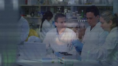 Laboratuar ekibi test tüpleri üzerinde çalışırken, oturan bilim adamı örnekleri inceliyor ve sürüş devresi görselleri üzerinde çalışıyor. Araştırma, yenilik, işbirliği, laboratuvar, teknoloji, analiz, bilim