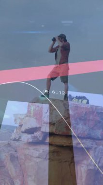 Dağlarda yürüyüş yapan beyaz bir adamın finansal verilerini işleme animasyonu. Küresel seyahat, finans, hesaplama ve dijital arayüz kavramı dijital olarak oluşturulmuş video.