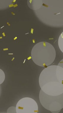 Altın noel konfetisinin gri arka planda ışık lekeleriyle düşüşünün animasyonu. Noel, kış, şenlik, gelenek ve dijital olarak üretilen video konsepti.