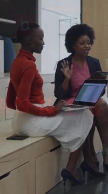 Animation of connected icons, numbers, letters, symbols on diverse coworkers discussing reports. Digital composite, multiple exposure, globalization, security, communication and technology concept.