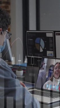 Animation of financial graphs over caucasian man in face mask having video call in office. Business, communication, technology and covdi 19 pandemic concept digitally generated video.