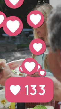 Sosyal ağ kalp ikonlarının animasyonu ve beyaz ailenin bahçede yediği yemeğin sayısı artıyor. aile, sevgi ve iletişim teknolojisi konsepti dijital olarak oluşturulmuş video.