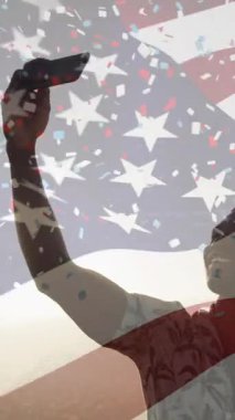 Amerikan bayrağı sallama animasyonu, konfetilerin Afrika kökenli Amerikalı bir adamın sahilde selfie çekmesi. Bağımsızlık Günü kutlaması ve tatil konsepti