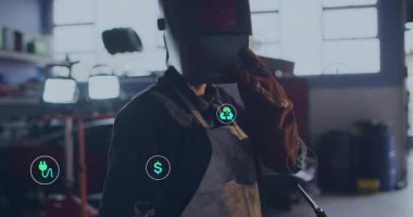 Enerji dolgusu ve karbondioksit simgeleri atölyenin etrafında dönerken kadın kaynakçı elinde meşale ve güneşlik tutuyor. Sanayi, zanaat, yenilik, sürdürülebilirlik, enerji, teknoloji, çevre