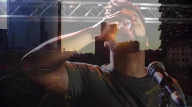 Sahne sanatçısı shot bardağı kapıyor, içiyor, kollarını ufuk çizgisi yansımasına kaldırarak kutluyor. Eğlence, performans, canlı müzik, kutlama, dinamik, kentsel, sahne