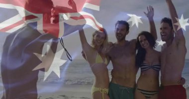 Seyahat fotoğrafçısı, Avustralya bayrağını dalgalandırarak kumsalda poz veren arkadaşları olarak kamerayı hedef alıyor. Tatil, dostluk, kutlama, açık hava, neşe, sahil, eğlence