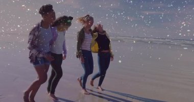 Suyun kenarında çıplak ayakla yürüyen dört kadın pazarlama içeriği için pastel konfeti fırlatıyor. Arkadaşlık, eğlence, kutlama, gündelik, açık hava, kaygısız, arkadaşlık