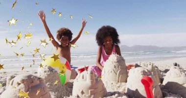 Kumdan kale inşa ettikten sonra kardeşler eğitim için altın yıldızlarla tezahürat yaparak kollarını kaldırdılar. Deniz kenarı, çocukluk, eğlence, kaprisli, neşeli, açık hava, kutlama